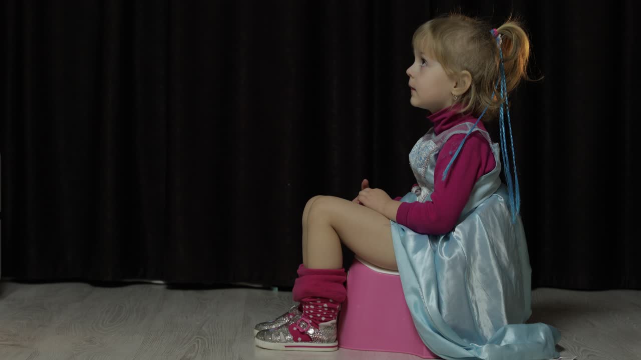 niña pequeña sentada en el baño y viendo la televisión