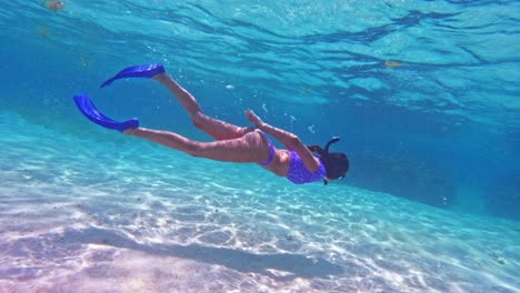 a girl snorkelling over white sand in caye caulker, belize