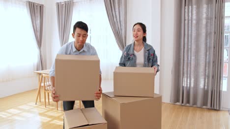 asian couple carrying cardboard box into the new home