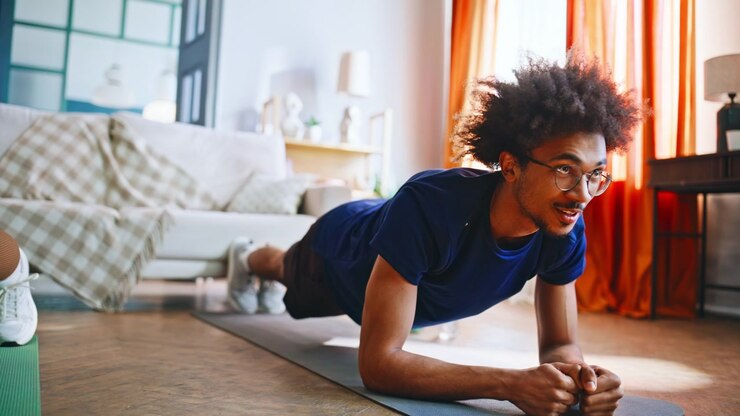 Multiracial couple holding plank exercise on mats. Home workout together.