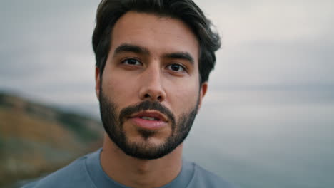 hombre mirando cámara paisaje marítimo nublado en el fondo de primer plano. retrato de un chico guapo