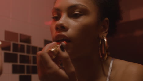 Close-Up-Of-A-Beautiful-Girl-Putting-Lipstick-On-While-Looking-At-Mirror-In-A-Bar-Bathroom-1