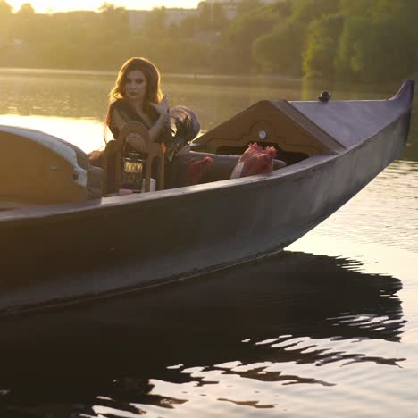 a beautiful woman with long hair is sitting in a gondola in an elegant dress at sunset. carnival in venice