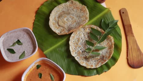 rotating south indian food set dosa with curry and chutney on yellow background