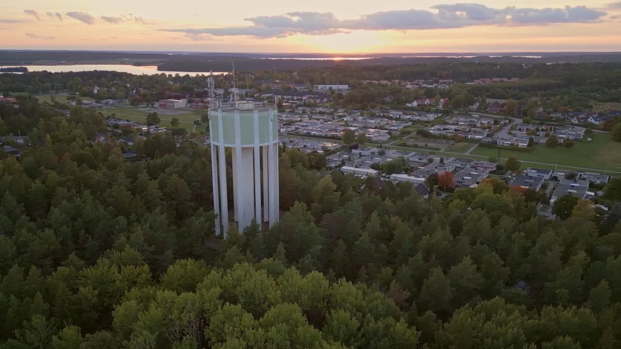 toma aérea de una torre de agua y un área residencial al atardecer