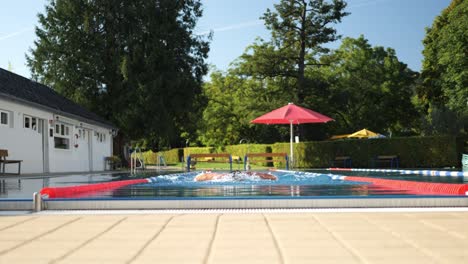 slow motion tracking shot of a swimmer swimming toward the camera public pool