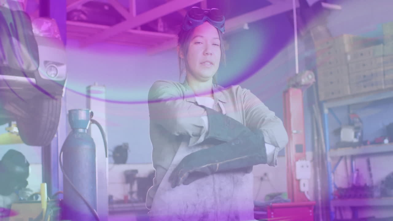 woman mechanic standing in automotive workshop, showing animated lift overlay and welding icon