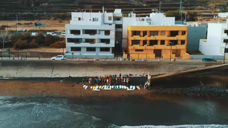 aerial slowmo: group of surfers on the beach in a funeral's ceremony in canary islands