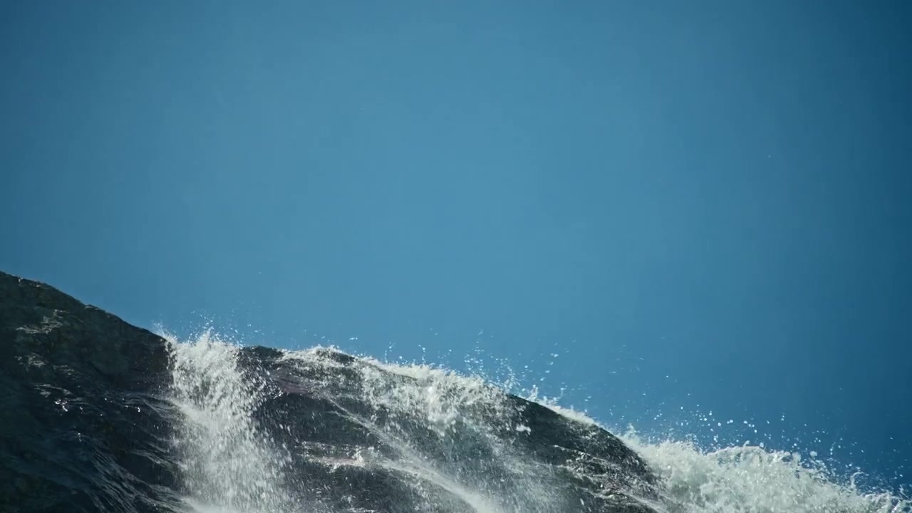 Powerful Waterfall Cascading Over Rocks Under a Bright Blue Sky