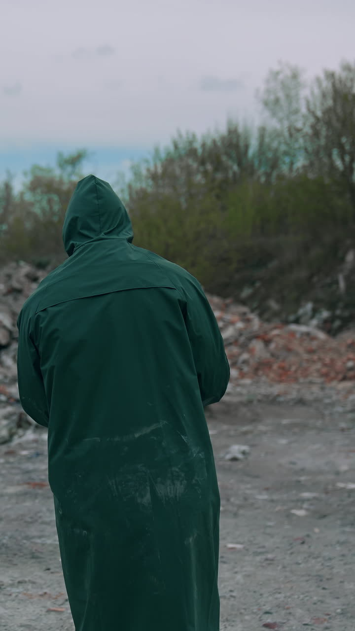 Virologist man in protective costume and respirator gas mask walking near landfill site pollution and looking at the scale of the disaster. Ecological disaster concept. Vertical video