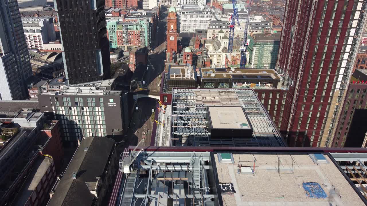 Aerial drone flight in Manchester City Centre over the rooftops of Oxford Road showing the buildings and streets below