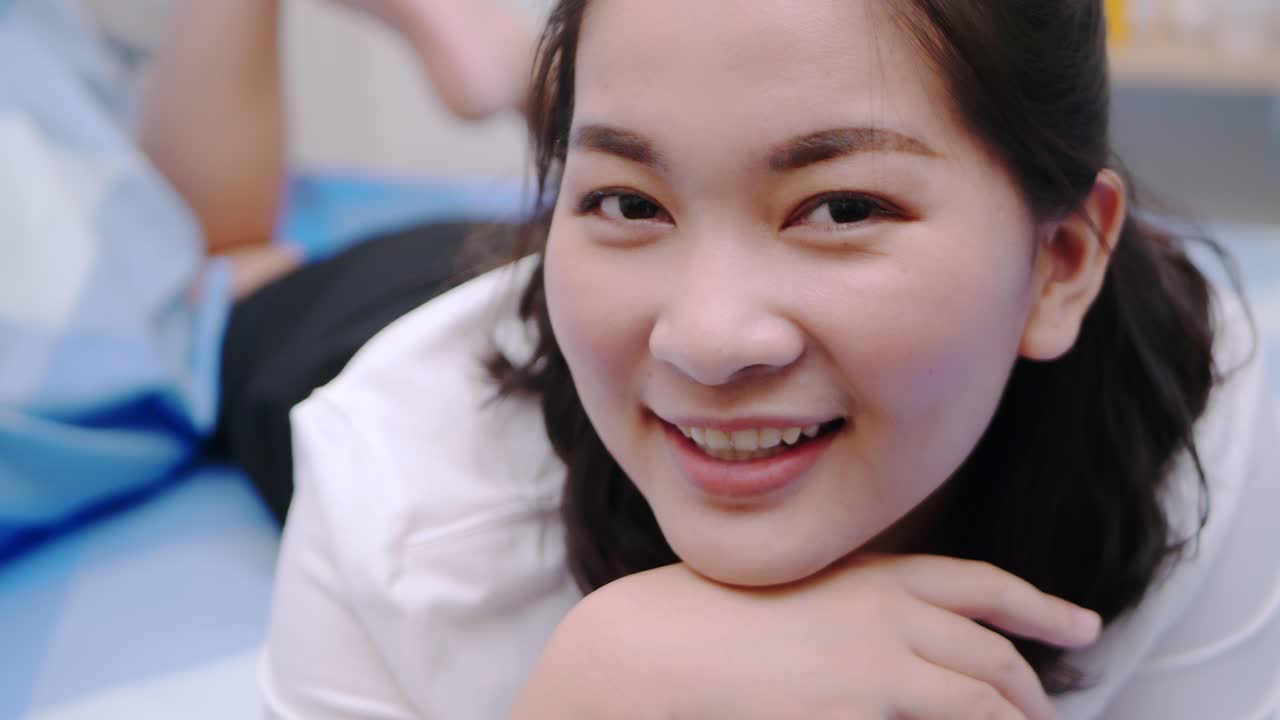 아름답고 웃는 아시아 여성들은 휴일에 침대에 누워 매우 행복하고 만족하며 맑은 빛, 느린 동작의 장면으로 휴식을 취합니다.