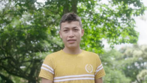 brunette man looks at the camera outdoors and smiles, surrounded by trees, exuding experience and confidence, his smile telling stories of wisdom