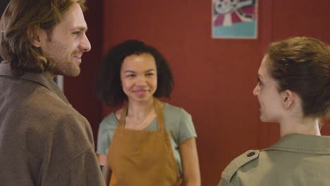 smiling female clerk selling movie tickets to a couple and the woman paying with a contactless card