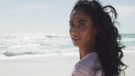 portrait of happy hispanic woman turning around on beach in sun