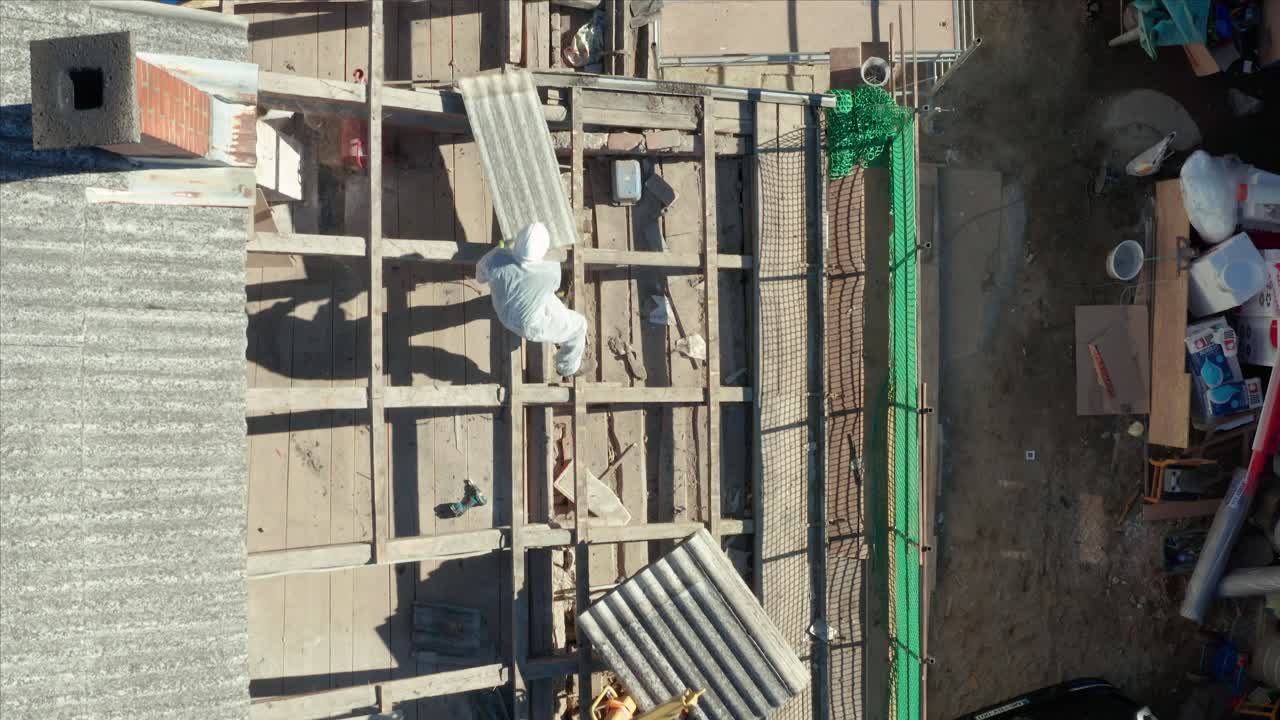 Top View Of Workers In Protective Suit Removing Asbestos-contained Roofs. aerial