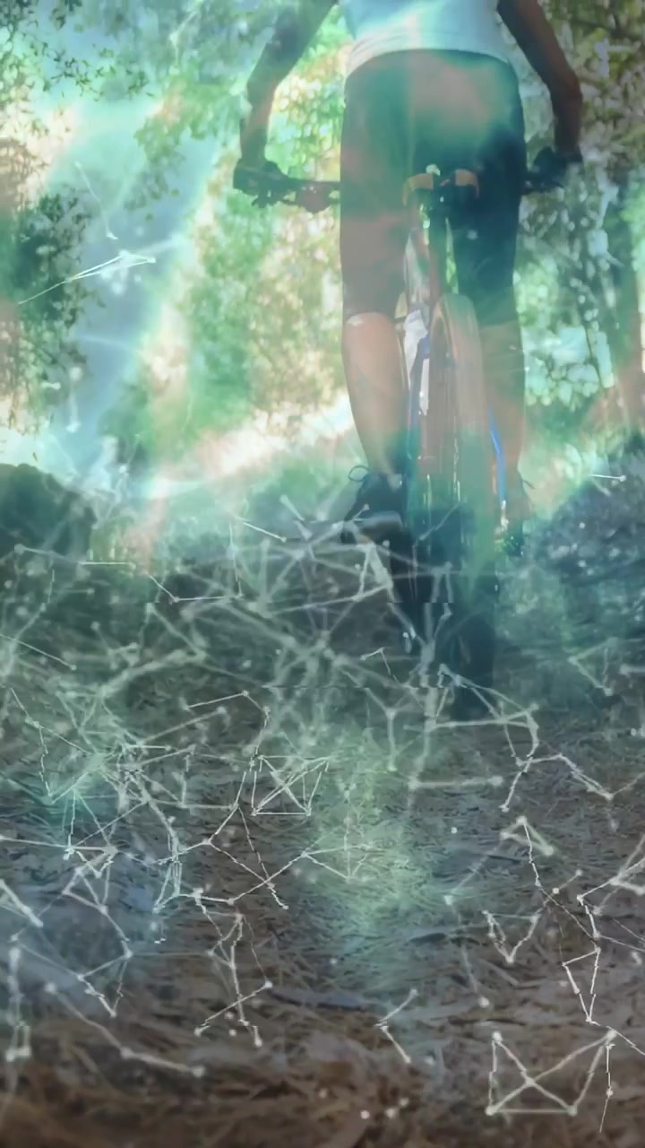 Vertical video: Female cyclist pedaling toward light on trail while tech overlay drifting over bike