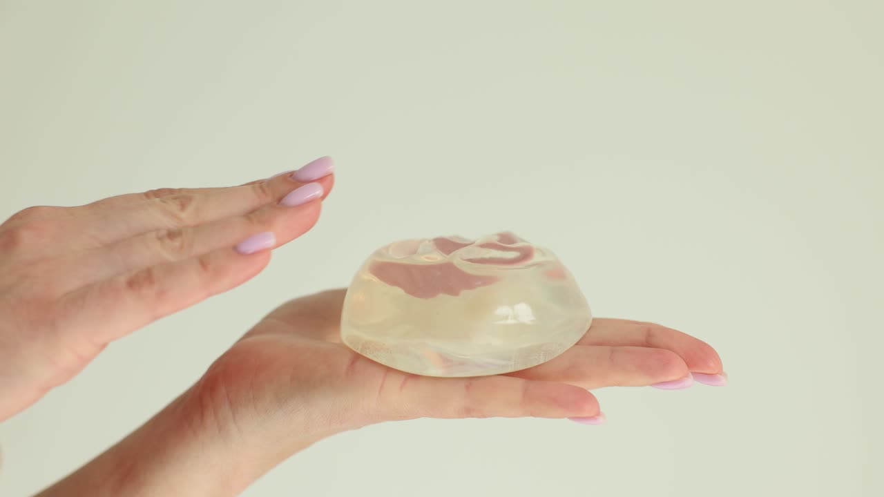 Hands demonstrating the flexibility of a breast implant