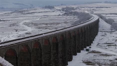 pullback establishing aerial drone shot of ribblehead viaduct in the snow in the yorkshire dales uk