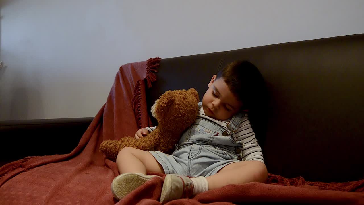 귀여운 피곤한 유아가 소파에서 잠이 들었습니다 - 재미있는 아기 얼굴 표정