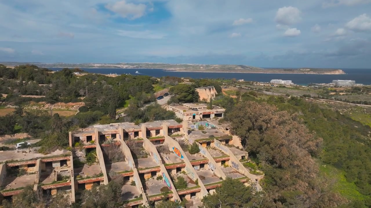 Campi verdi e hotel abbandonato del festival a Mellieha, Malta, con Gozo sullo sfondo - Ripresa aerea con drone