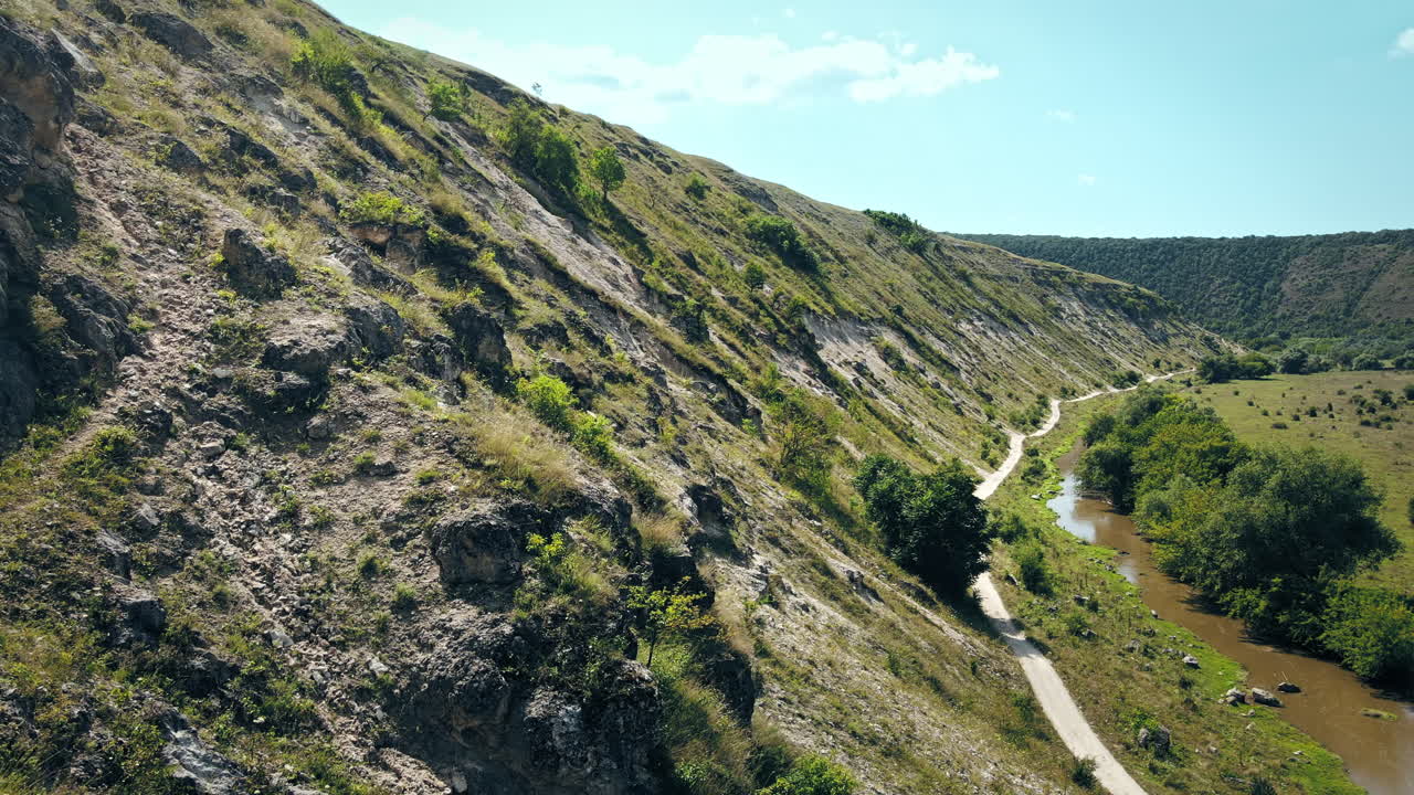 Aerial drone view of a valley with floating river, rock on the foreground, hill slopes and greenery in Moldova