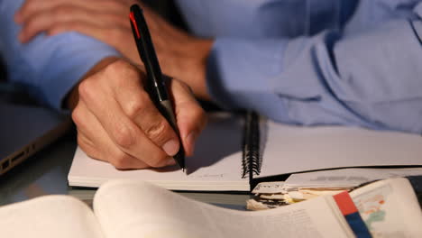 businessman writing in notebook at night