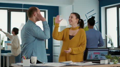 Smiling-coworkers-in-startup-office-doing-high-five-hand-gesture-celebrating-good-sales-and-high-profit