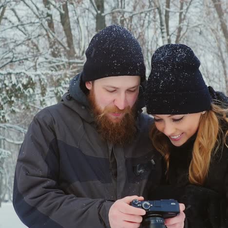 Young-Couple-Viewing-Photos-On-Camera-In-Winter