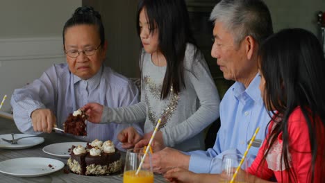 front view of old senior asian grandmother serving birthday cake in a comfortable home 4k