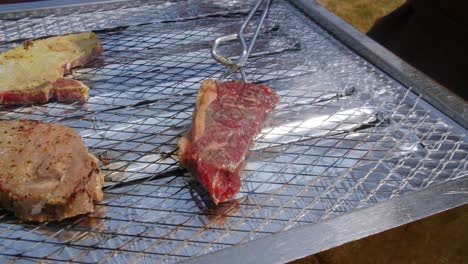 piece of meat being placed on top of a barbecue to be grilled