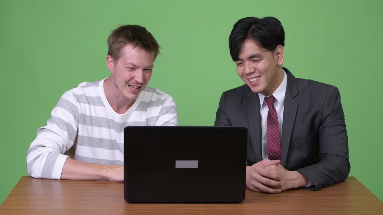 젊은 아시아 사업가와 젊은 스칸디나비아 사업가가 노트북으로 함께 일하고 있습니다.
