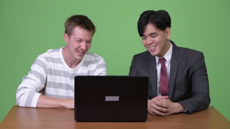 joven empresario asiático y joven empresario escandinavo trabajando juntos con una computadora portátil