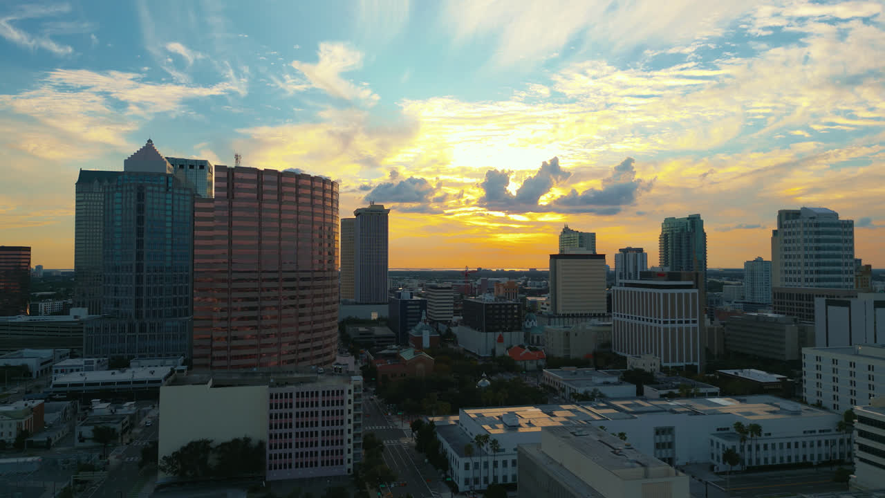 Tampa skyline at sunset as beautiful colors fill the sky and illuminate the clouds, aerial tracking left