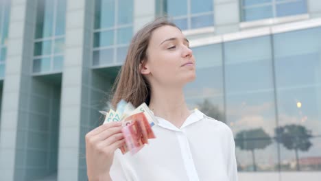 young caucasian successful business woman is waving with banknotes in hand