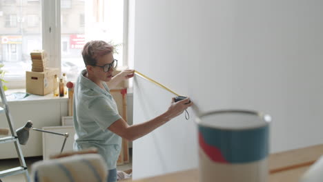 woman measuring wall with tape measure