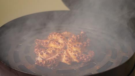 바비큐 그리드 스모커에서 숯불에 향신료와 허브를 곁들인 맛있는 쫄깃한 문어 요리