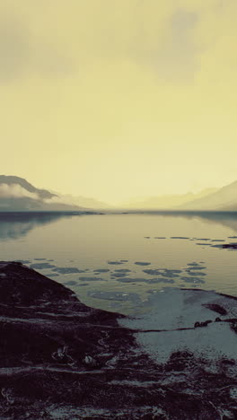 expansive landscape revealing serene water and distant mountains at dusk