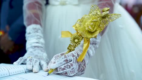 a bride signs the marriage contract using an elegantly decorated pen in gold