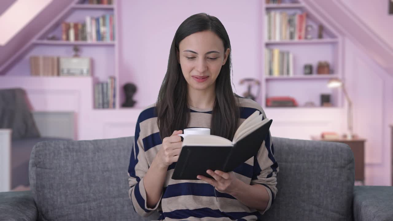 chica india feliz leyendo un libro y bebiendo café