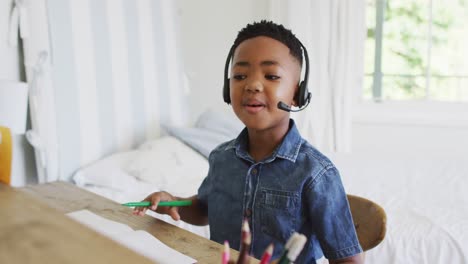 Portrait-of-african-american-at-home-in-online-school-class,-using-headset-looking-at-camera