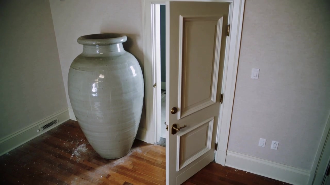 Opening interior door swinging outward in residential room, urn remaining against wall with dust