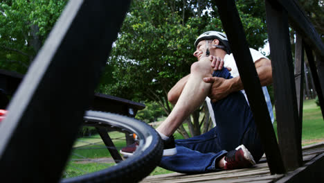 ciclista caído sosteniendo su rodilla lesionada