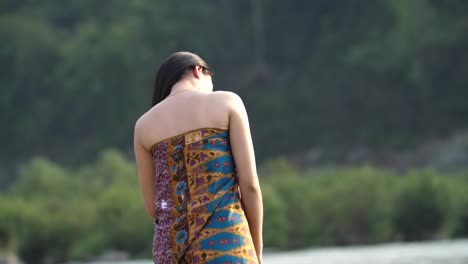 woman in traditional indonesian batik dress by a river