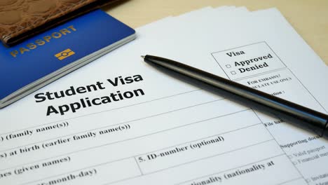 student visa application form with passport and pen