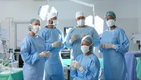 portrait of diverse surgeons wearing surgical gowns in operating theatre, slow motion