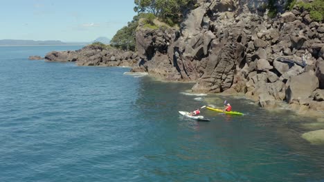 dos kayakistas remando a lo largo de la costa de la isla ballena moutohora, pintoresca nueva zelanda