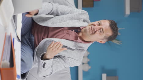 vertical video of home office worker old man looking at camera with disgust and hatred.