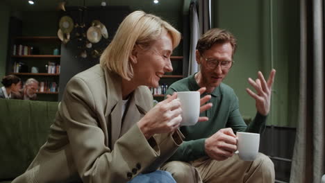two people having a relaxed conversation over coffee in a lounge