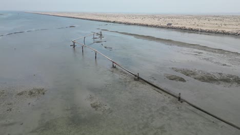 river with low water level next to desert terrain, irrigation pipes